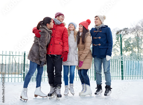 happy friends ice skating on rink outdoors
