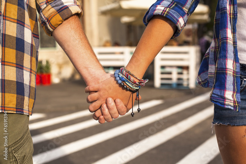 Young couple walking in the City holding hands, close-up.