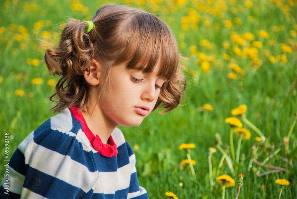 Offended little girl with pigtails on background of dandelions Offended little girl with pigtails on background of dandelions