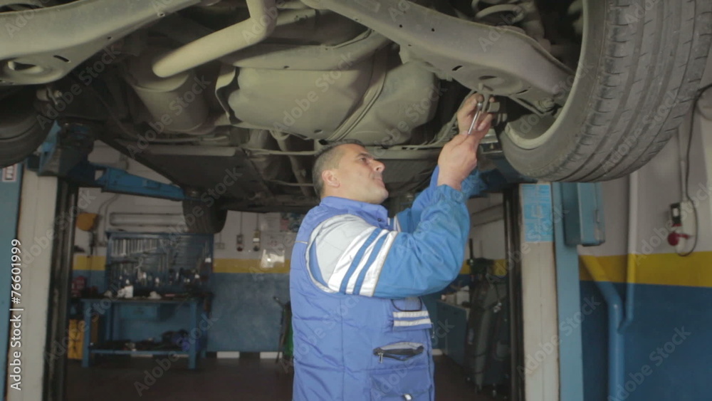 Auto mechanic repairing a car ( under a car lifts) - dolly Auto mechanic repairing a car ( under a car lifts) - dolly
