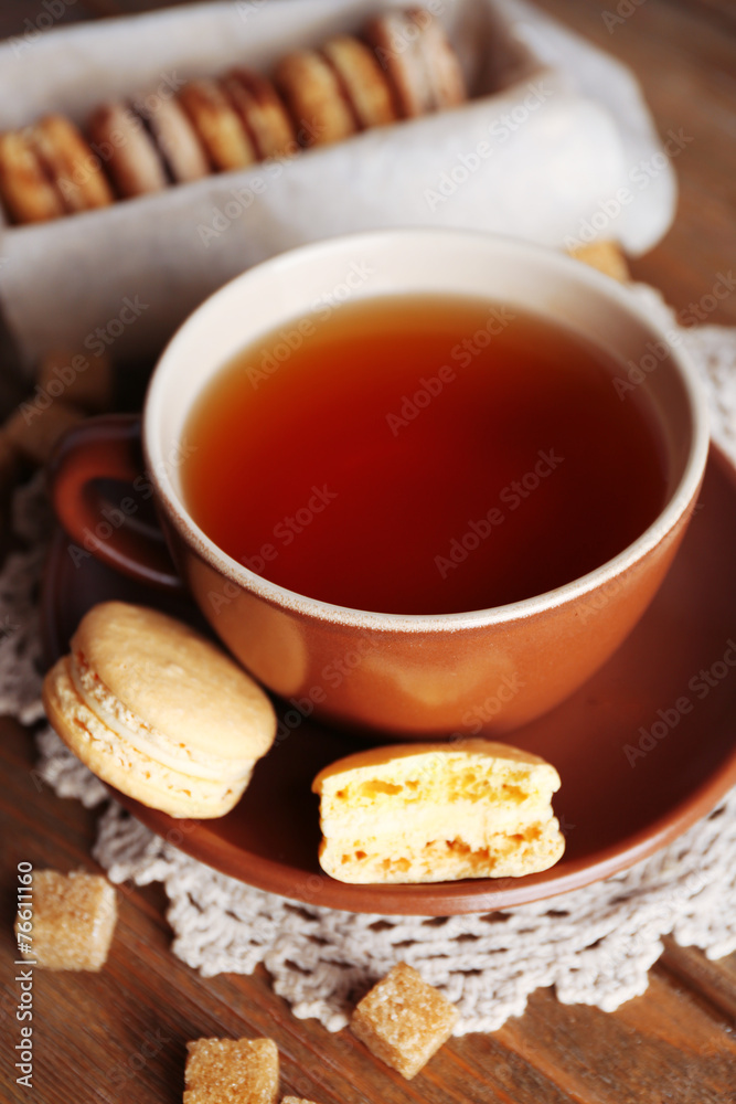 Colorful macaroons with cup of tea on wooden background Colorful macaroons with cup of tea on wooden background