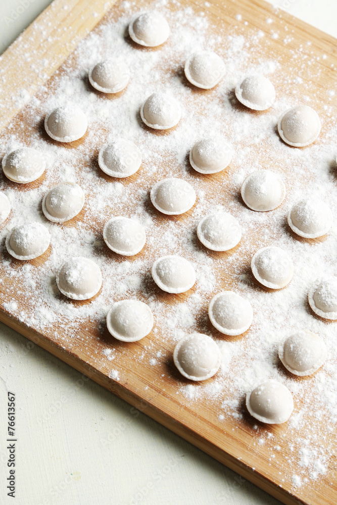 Raw dumplings on cutting board on table close-up