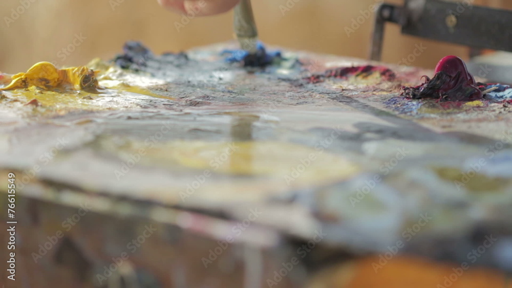 painter mixes with the brush colors in his palette painter mixes with the brush colors in his palette