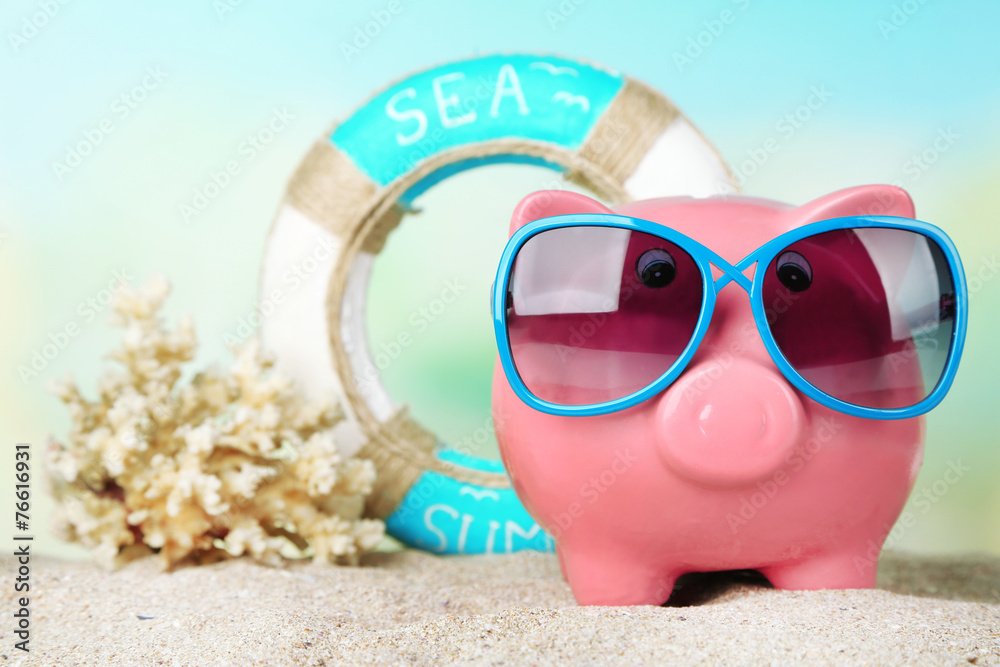 Piggy bank with sunglasses on the beach