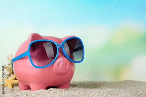 Piggy bank with sunglasses on the beach © Africa Studio