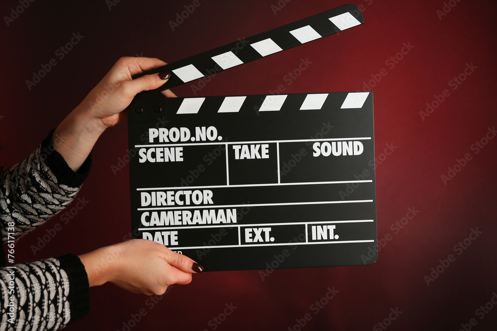 Movie clapper in female hand on dark color background