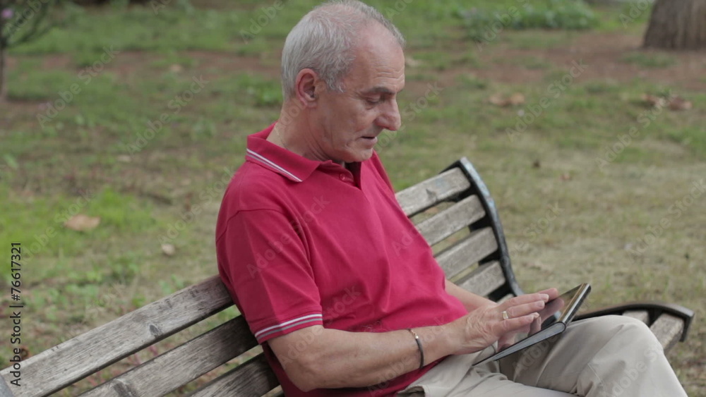 Friendly handsome old man with tablet computer in park Friendly handsome old man with tablet computer in park