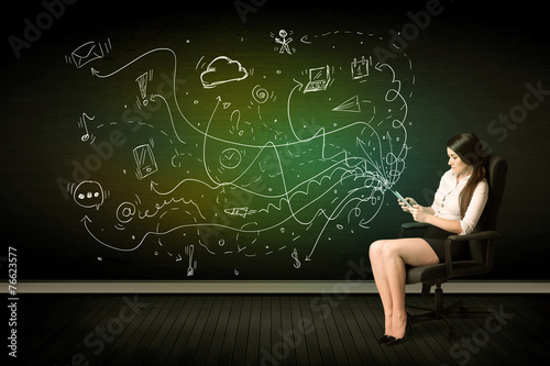 Businesswoman sitting in chair holding tablet with media icons
