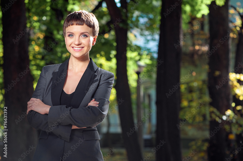 Attractive smiling young woman keeping arms crossed at the park Attractive smiling young woman keeping arms crossed at the park