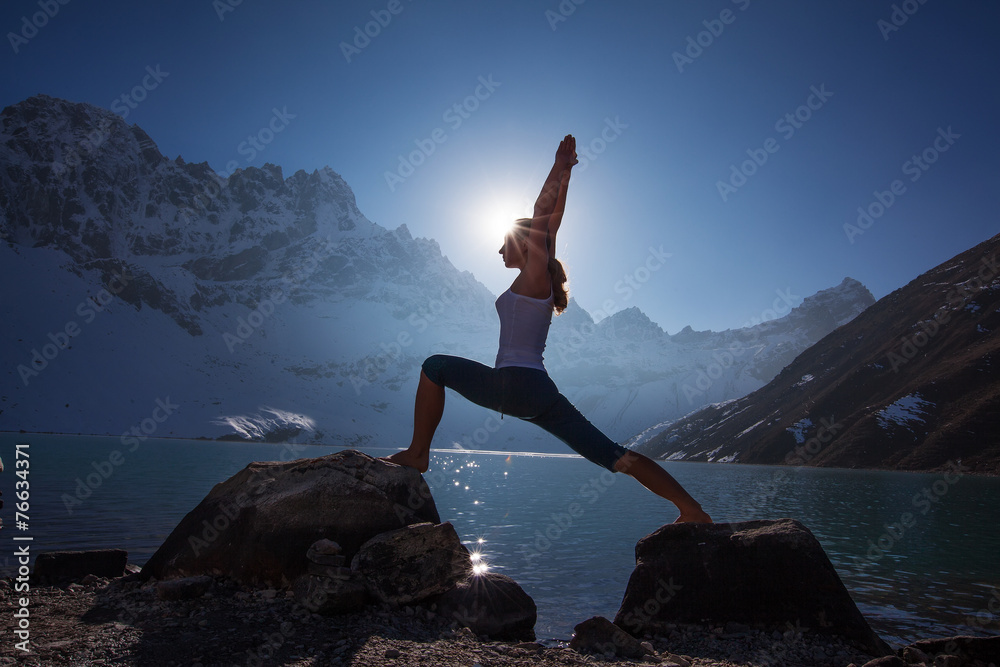 Young woman is practicing yoga at mountain lake