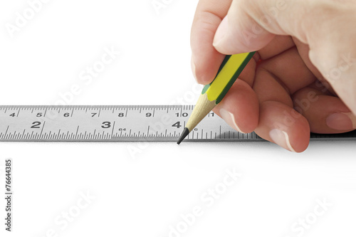 Horizontal photo of female hand using ruler and pencil on white