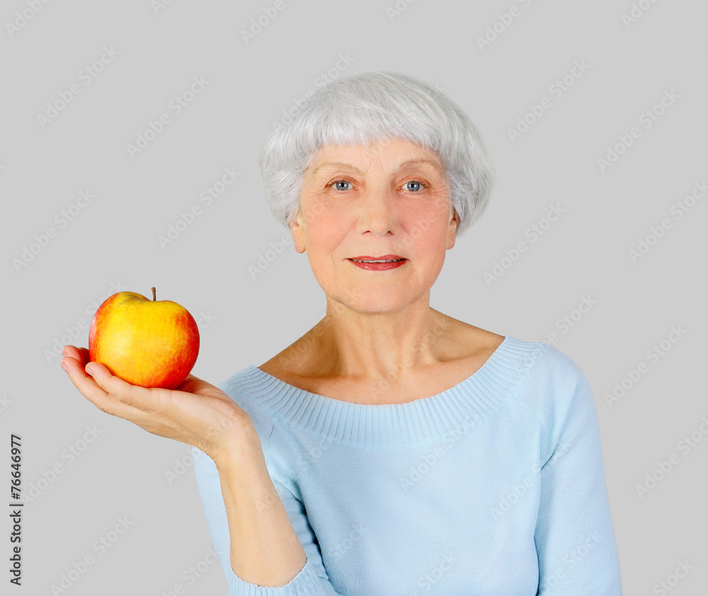 elderly woman with red apple in hands on a light background elderly woman with red apple in hands on a light background