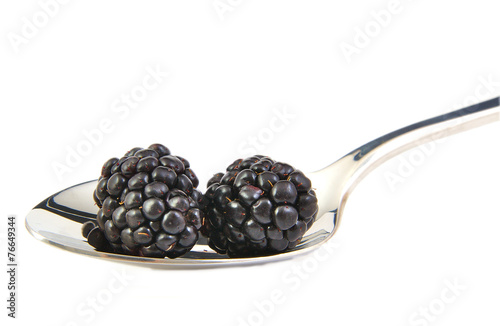 Blackberries in a metal spoon on white background.