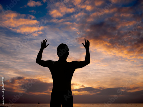 Silhouette of man surrendering with two hands raised in air near