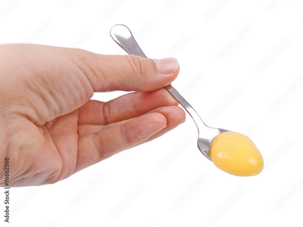 Spoon with vanilla pudding, baby food in hand on a white backgro