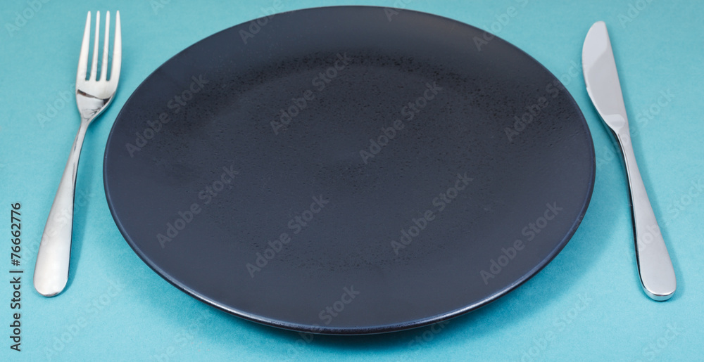 dinner black plate with fork and knife on green dinner black plate with fork and knife on green
