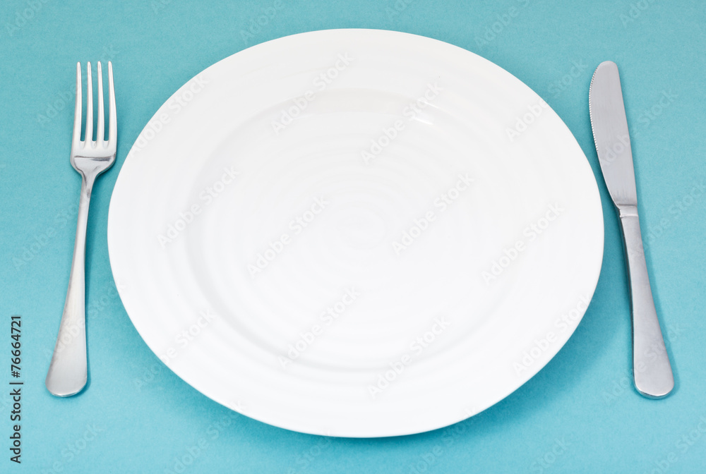 empty white plate with fork and knife on green