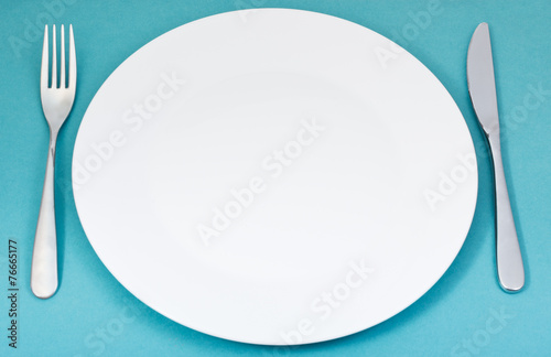 white porcelain plate with fork and knife on green