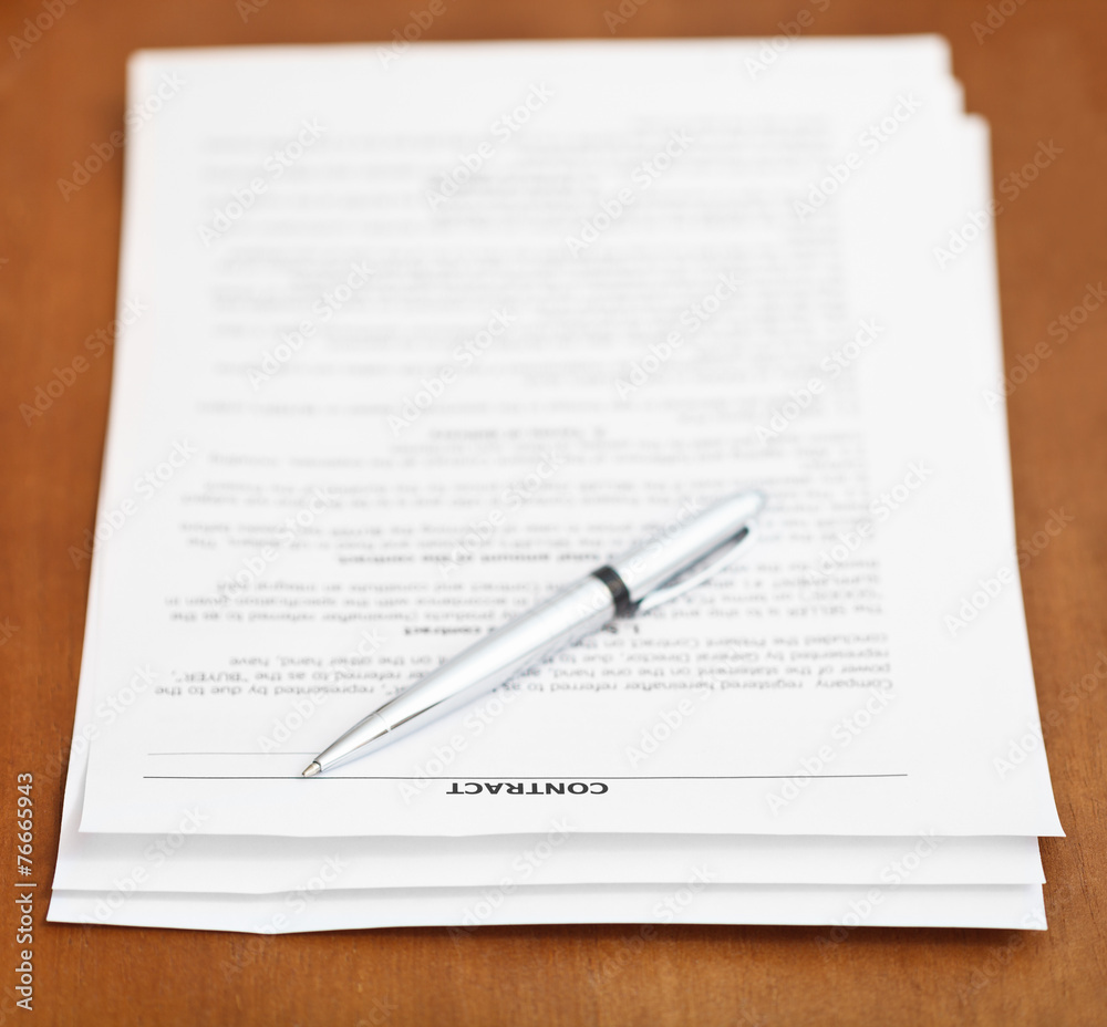 sheets of contract and silver pen on wooden table sheets of contract and silver pen on wooden table