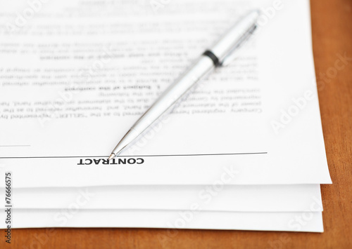 pages of sales contract and silver pen on table