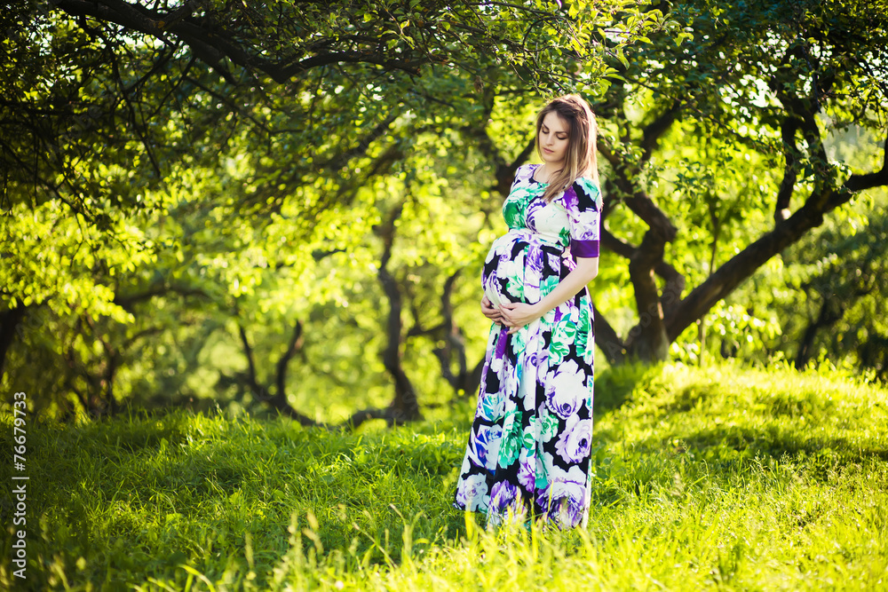 Beautiful pregnant woman in sunny park