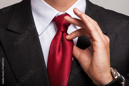 Photographie Businessman adjusting his necktie