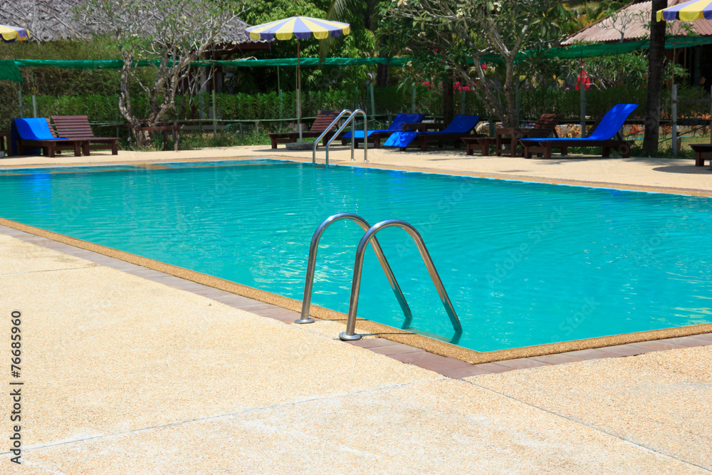 Swimming pool with relaxing seats and sun umbrella