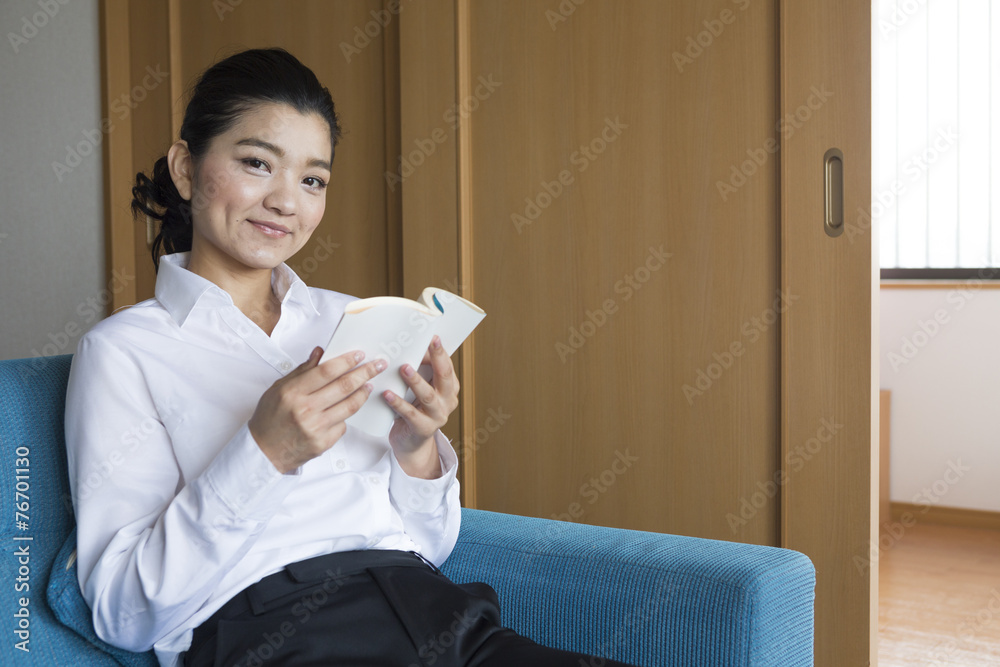 部屋で読書をするOL