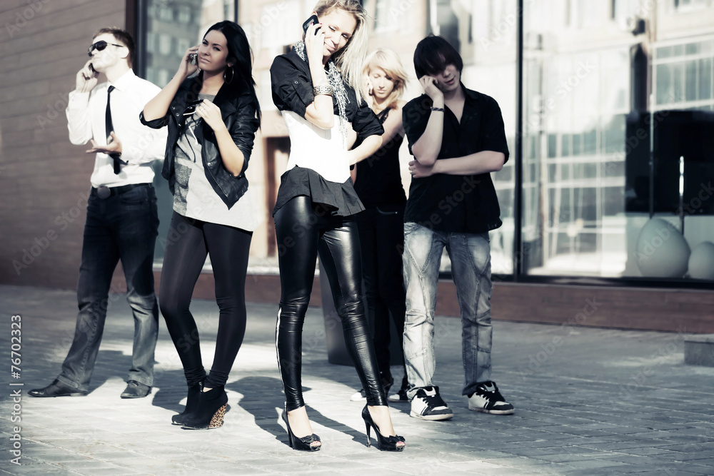 Group of young fashion men and women calling on the phones