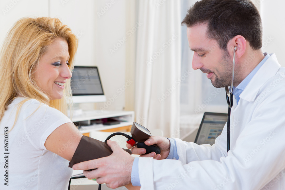 Fototapeta premium Young attractive doctor checking patient's blood pressure