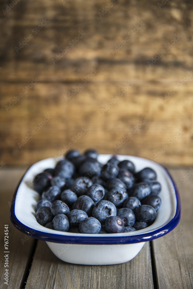 Blueberries in rustic kitchen setting with old wooden background