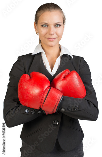 Businesswoman wearing boxing gloves, arms crossed on her breast