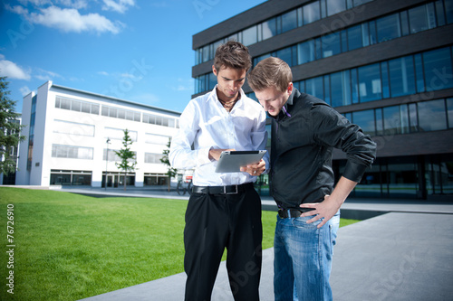 Two businessmen discuss a project on a tablet computer photo