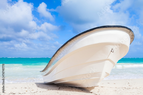 Fototapeta Naklejka Na Ścianę i Meble -  White boat lays on sandy beach, ocean coast