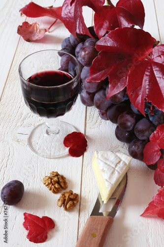 French cheese Coulommiers, wineglasse, red grapes and autumn lea photo