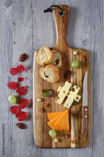Cheese plate: Gouda cheese, green grapes and red autumn leaves