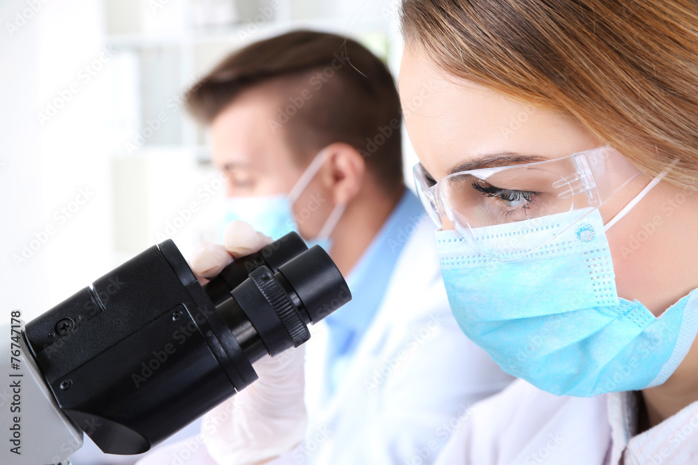 Young female and male scientists with microscope in laboratory Young female and male scientists with microscope in laboratory