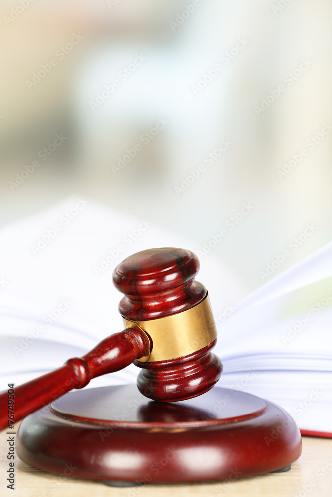 Wooden judges gavel lying on law book, close up