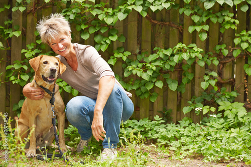   ltere Frau mit Hund im Garten