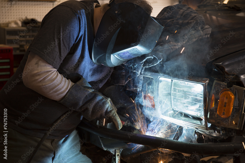 Man welding the bumper of a vehicle Man welding the bumper of a vehicle