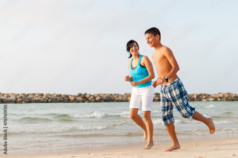 Mother with her son are running on the beach and having fun