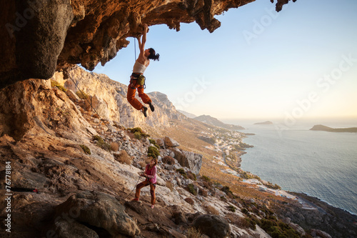 Young woman climbing on cliff, female partner belaying © Andrey Bandurenko