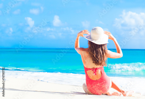 Fotografía back view of long haired girl in red swimsuit and straw hat on