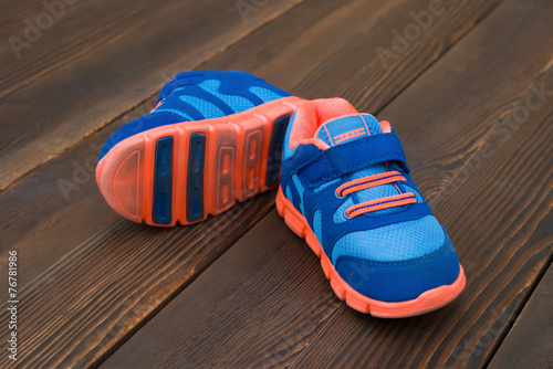 pair of blue sporty shoes for kid on wood © Freer
