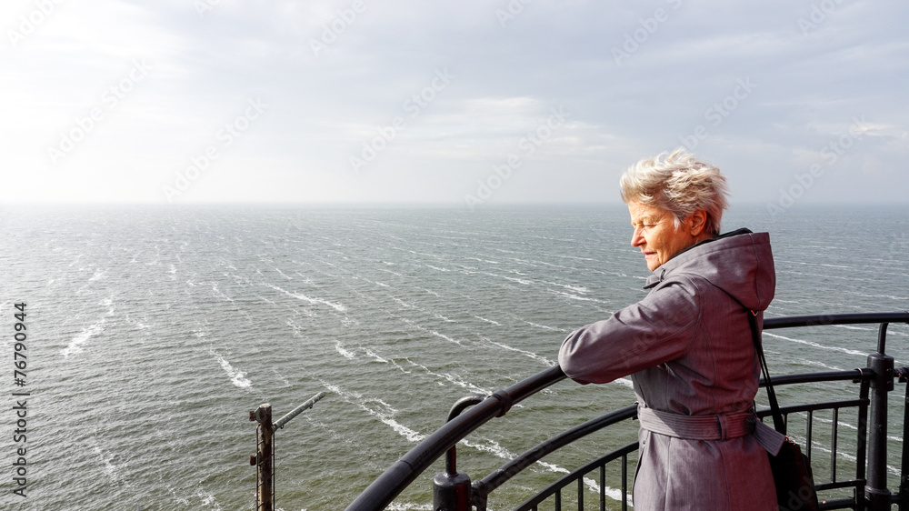 Woman looking over het IJselmeer from the lighthouse in Urk, an historic fishing village in the Netherlands - obrazy, fototapety, plakaty 