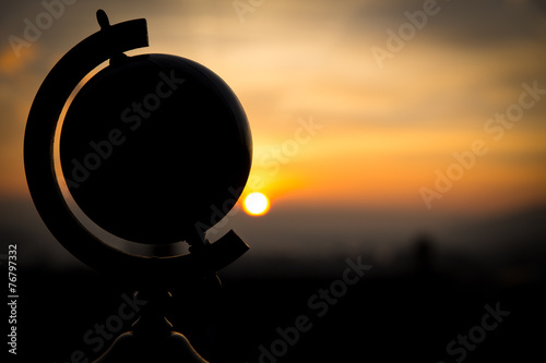 Canvastavla Silhouette eines Globus vor einem Sonnenuntergang, Konzept Reise