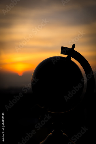 Silhouette eines Globus vor einem Sonnenuntergang, Konzept Fernw photo