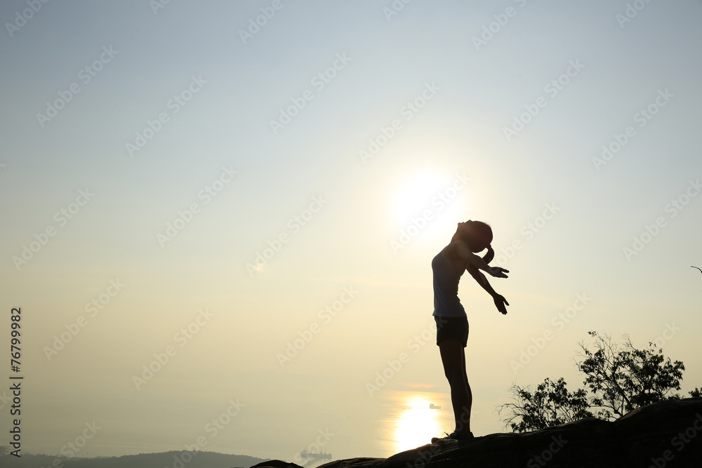 cheering young woman hiker open arms at sunrise mountain peak 