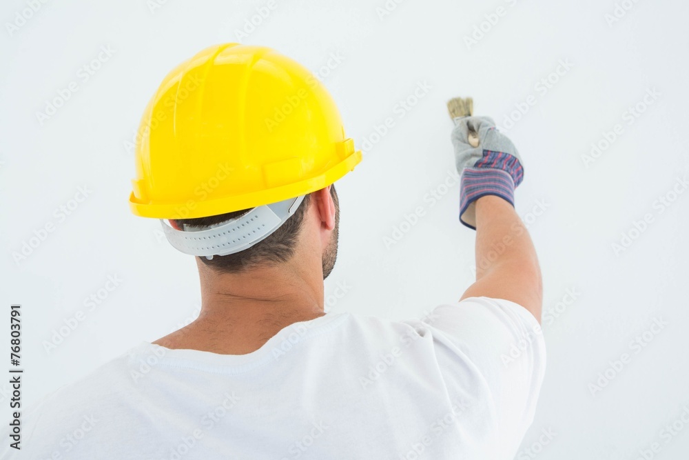 Man wearing hard hat while using paintbrush Man wearing hard hat while using paintbrush