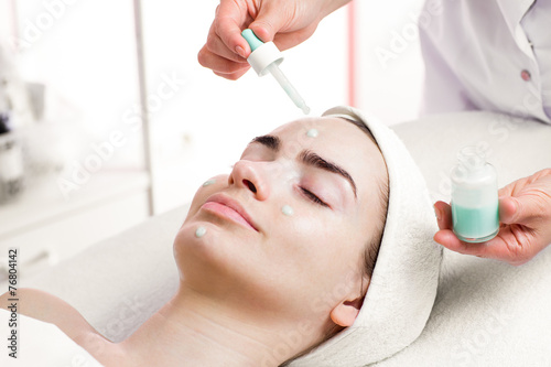 Serum facial treatment of young woman in spa salon photo